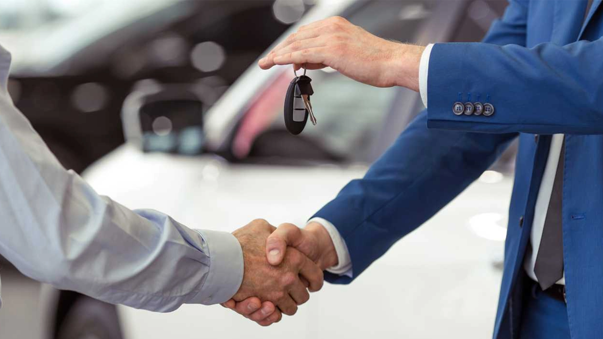 A close-up of a professional handshake, with one person handing over car keys to another, signifying a successful RTA Registration Service.